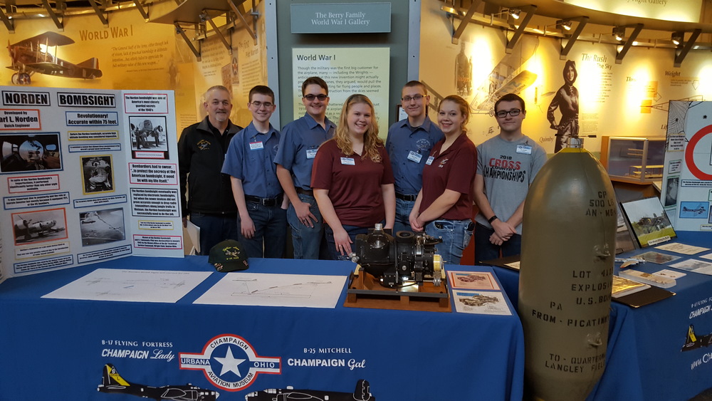 Aviation students at the family fun event standing behind their table.